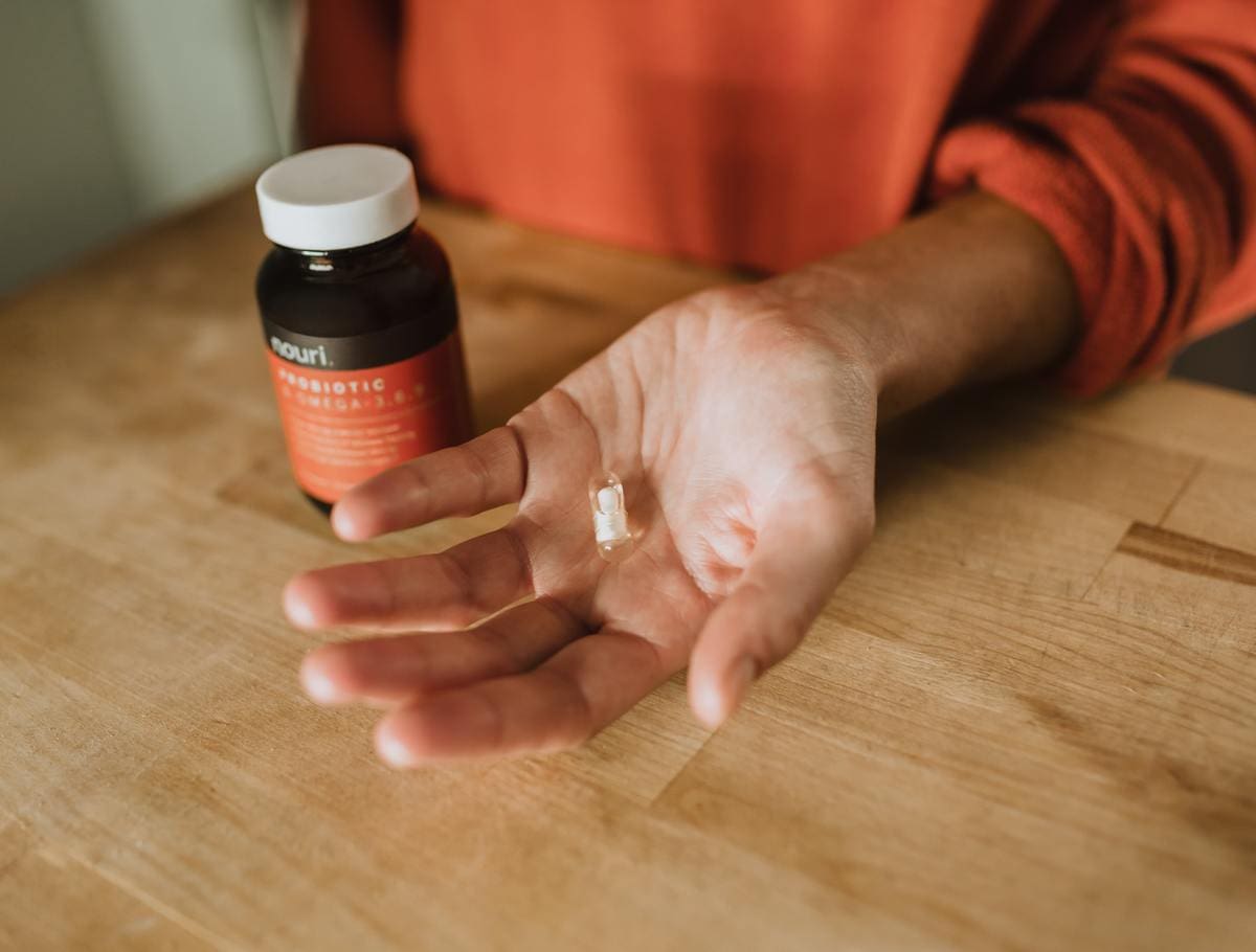 A man holding out his hand with a probiotic pill in his hand