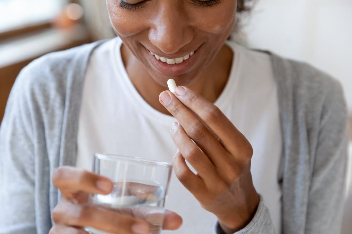 Close up of a happy young woman taking her daily dose of probiotics